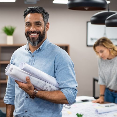 Portrait,Of,Multiethnic,Architect,With,Blueprints,In,Creative,Office.,Mature